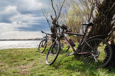 Two mountain bikes stand on the river bank. Atmospheric dynamic light. Picnic