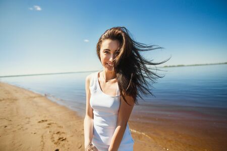 Portrait of beautiful sexy happy girl on the sand city beach with sea background. Young smiling woman having fun, flirting and dancing against blue sky and water. Summertime carefree conceptの写真素材