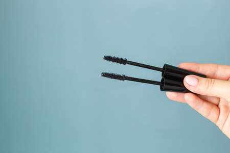 Woman holding mascara makeup brushes on the soft blue copyspace backgroundの写真素材
