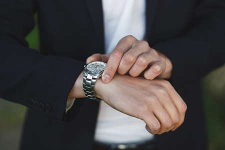 Groom or businessman looking at his watch on his hand, watching the time in the park. Wrist Closeup.