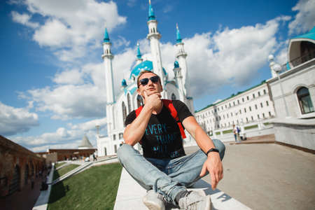 Handsome male tourist in glasses on the background Kul Sharif Mosque lis the main symbol of Kazan and touristic attraction. Kremlin, Kazan, Tatarstan, Russiaの写真素材