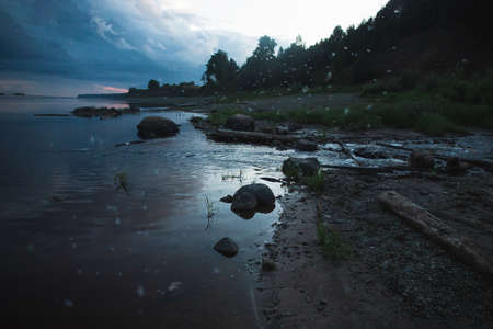 Blue mistycal night landscape with fireflies and forest river coast. Northern Dvina river, Russia.
