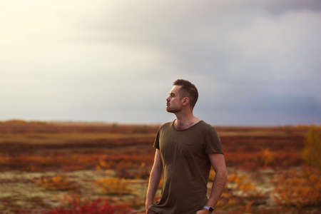 Young man enjoying in red colors of autumn tundraの写真素材