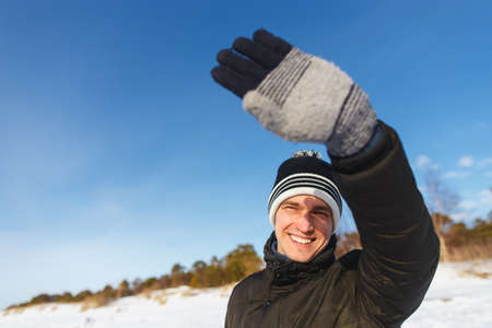 People, christmas, winter and season concept - happy smiling man in jacket and winter hat enjoying sunny winter dayの写真素材