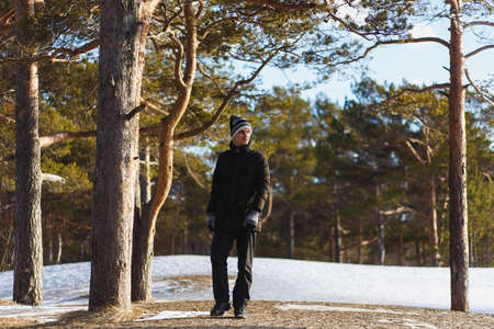 Young caucasian man in a warm winter clothes in the coniferous winter forest in north Russiaの写真素材