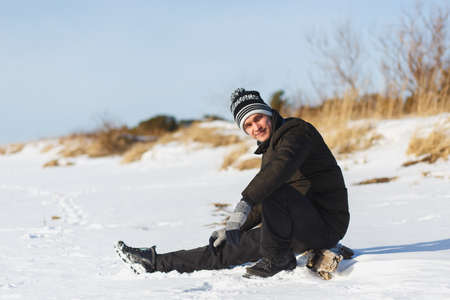 Young caucasian man in a warm winter clothes sitting in the coniferous winter forest in north Russiaの写真素材
