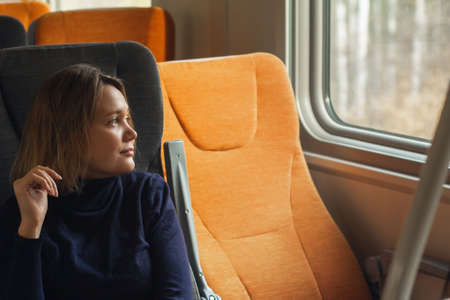 Young woman traveler looking to window inside of suburban trainの写真素材