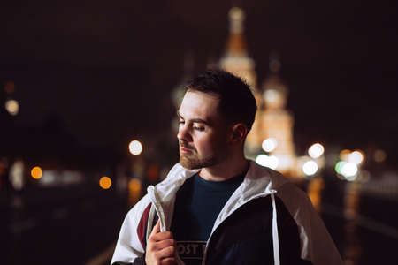Handsome man in a windbreaker poses overnight in Red Square