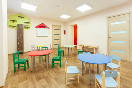 Colorful tables for classes for children and light beige colored game room in the kindergartenの写真素材