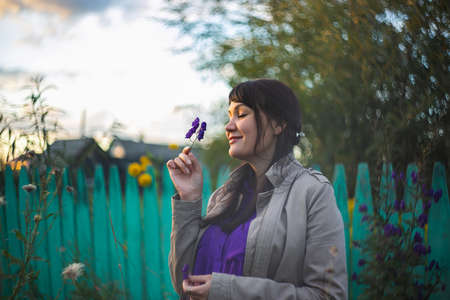 Beautiful young woman smells a purple flowers outdoorsの写真素材
