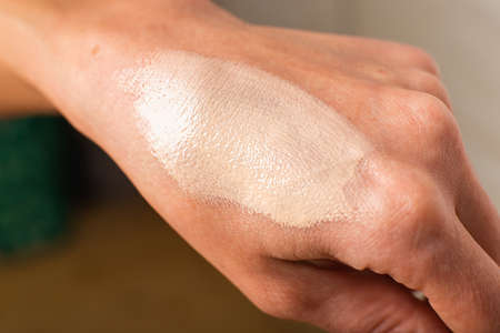 Swatch of tonal foundations on the woman hand closeup texture