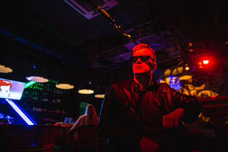 Handsome man in leather jacket with sunglasses and neon lightsの写真素材