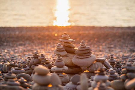Stones pyramid on pebble symbolizing zen, harmony, balance. Ocean at sunset in the background