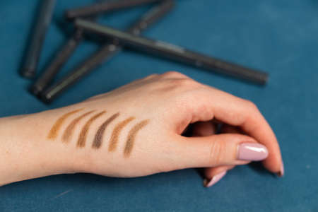 Different colors of mascara for eyelashes on female hand on blue background, closeupの写真素材