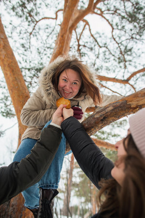 Funny girl sitting on a pine tree like a squirrel and eating cakes from hands.