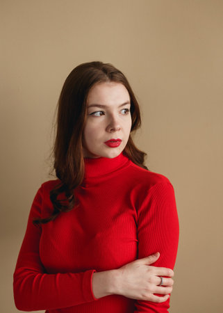 Close up young attractive woman 20s in red turtleneck isolated on plain pastel beige background studio. People lifestyle conceptの写真素材