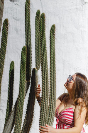 A joyful woman gleefully engages in a playful moment with a magnificent cactus, creating a cherished summer memoryの写真素材