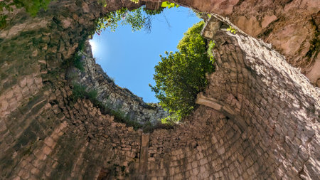 A breathtaking view from an ancient stone well, displaying an array of vibrant greenery beneath a...