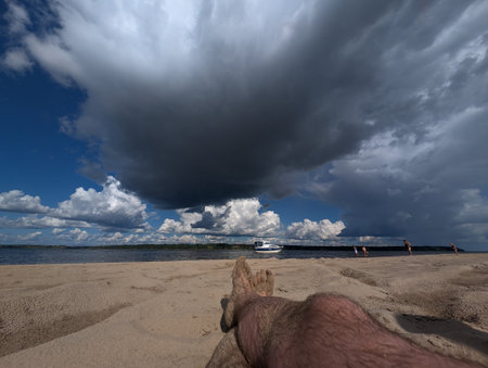 A serene beach view featuring a sandy shore and dramatic clouds gathering overhead, perfect for relaxation or nature-themed projects.の写真素材