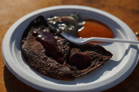 A tempting plate features a delicious crepe topped with jam and syrup, perfect for a satisfying breakfastの写真素材