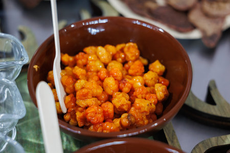 A closeup view of vibrant and colorful orange spicy snack items arranged in a brown bowl, ideal for party treatsの写真素材