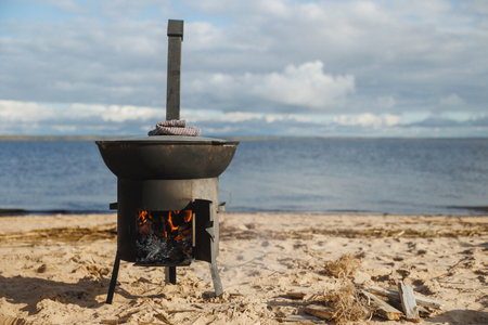 A stove is burning by the beautiful beach, creating an ideal atmosphere perfect for outdoor cooking adventuresの写真素材