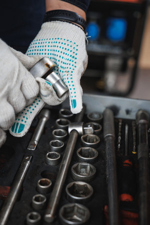 A diligent individual, dressed in protective gloves, is carefully positioning a wrench above a...