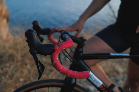 CloseUp Of Red Handlebar And Hand Gripping Brake Lever On Gravel Bike, Sharp Texture Of Tape And Cableの写真素材