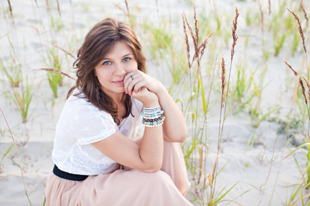 Beautiful dreaming girl sitting on the sandの写真素材
