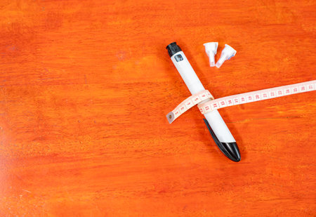 Pen needle and waist measurement tape on wooden table background. concept of result diabetic.の写真素材