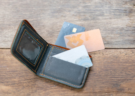 A vintage brown leather wallet with credit card open on a weathered wooden table.の写真素材