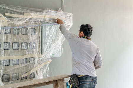 The technician is measuring the electric meter box to install additional equipment in new building.の写真素材