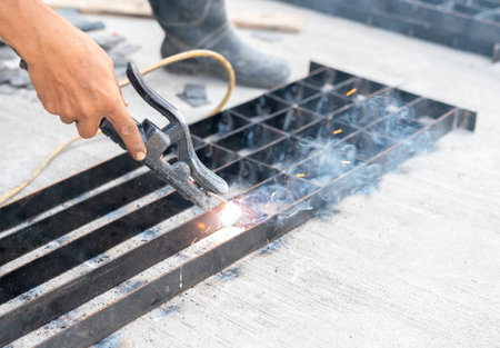 Worker welding drain water grill.