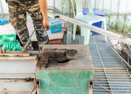 The workers are bending rebar using a rebar bending machine at construction site.