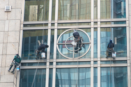 Group of men cleaning window outside building