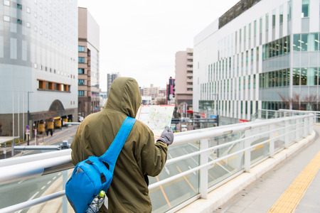 Male tourist holding map and try to find the way in kumamoto city japan.