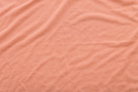 Close up of beautiful wrinkle coral color bedsheet fabric texture.の写真素材