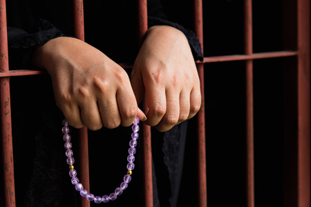 Close up hand of muslim woman holding bead hang on iron bar in jal.の写真素材