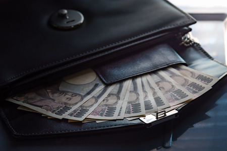 Close up of ten thousand yen banknote call ichiman  banknote in japan inside black business leather bag for traveler.の写真素材