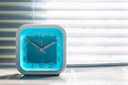 Close up of white square alarm clock on cabinet in the moring.