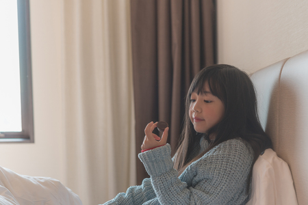 Close up of cute asian girl eating chocolate in hotel room.の写真素材