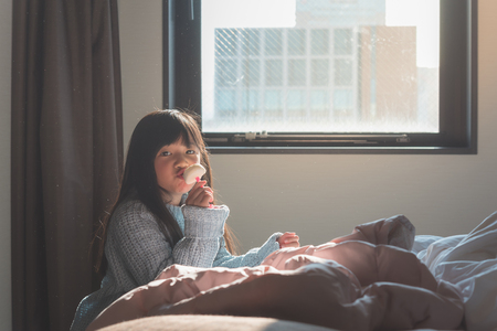 Close up of cute asian girl eating white chocolate ice cream in hotel room.の写真素材