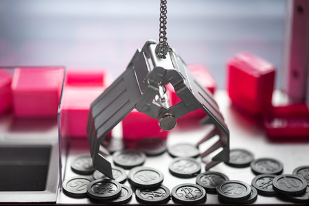 Close up of electronic claw tryin to catch virtual plastic coins.の写真素材