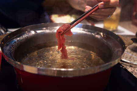 Close up of chopstick holding local beef for cooked in shabu pot Tokyo Japan.の写真素材