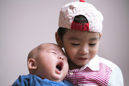 Duo portrait of sibling with little yawning babyの写真素材