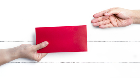 Shot of handover of Red packets for Chinese New Year Gifts on the white wooden plank, Traditional Celebration Chinese New Year.の写真素材
