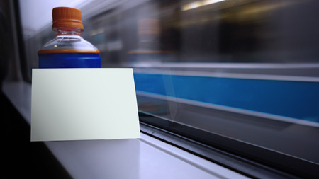 Blank white card put on the bottle near by windows shield with blurred background of transportation, copy spaceの写真素材