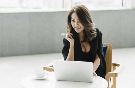 Young businesswoman sitting on the chair and working with laptop.の写真素材
