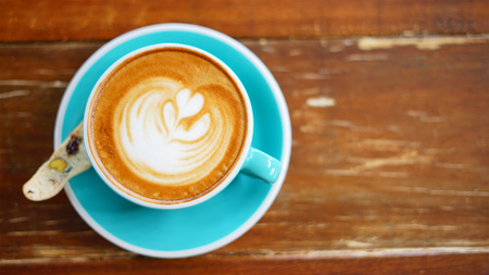 Flat lay of latte art on the blurred wooden table with copy space.
