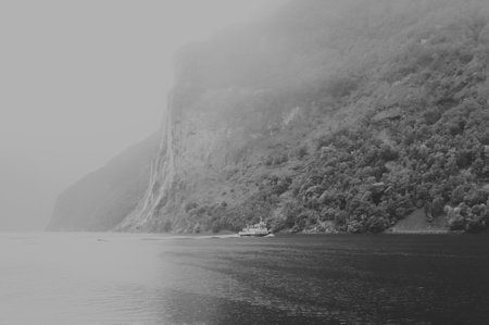 black and white view of a waterfall in a fiord in norway in a foggy and rainy dayの写真素材